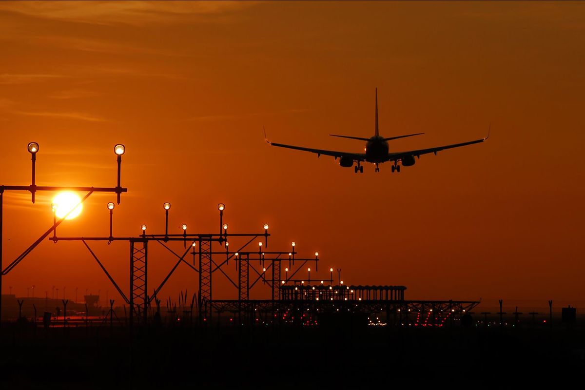 Aircraft on final approach over the runway lights at sunrise, for early Manchester Airport flights