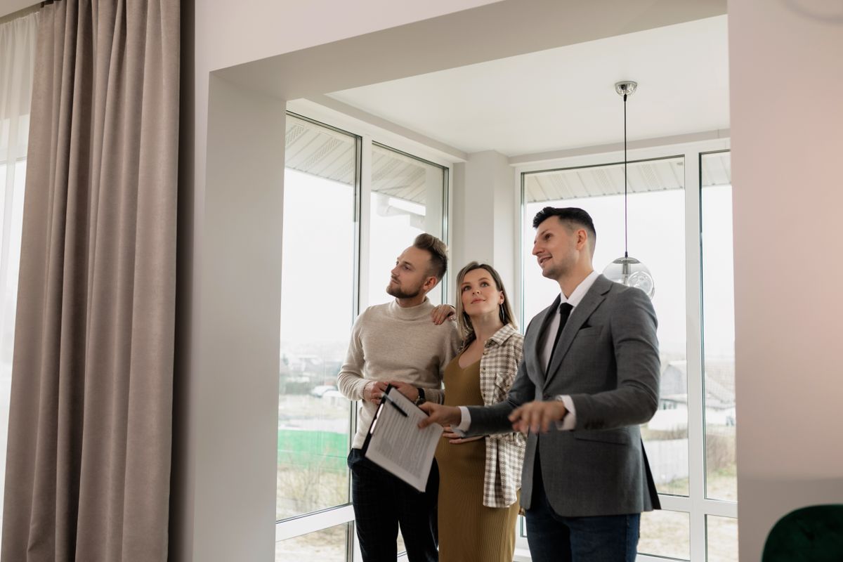 Couple viewing a home with an agent while weighing selling against guaranteed rent